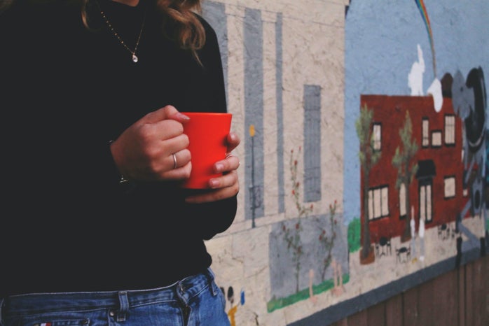 the lala girl holding mug in front of mural?width=698&height=466&fit=crop&auto=webp