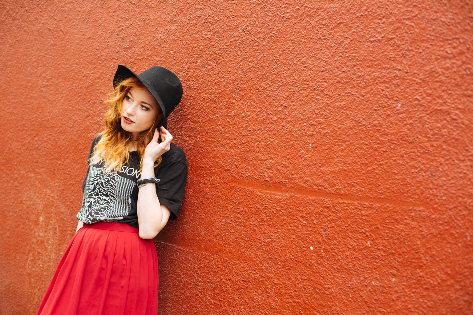 Girl Against Red Wall Red Skirt And Band Tee