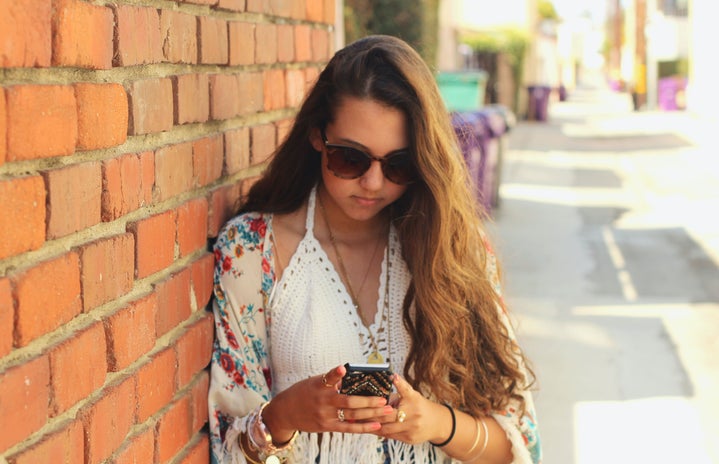 Kellyn Simpkin-Girl Next To Brick Wall Texting
