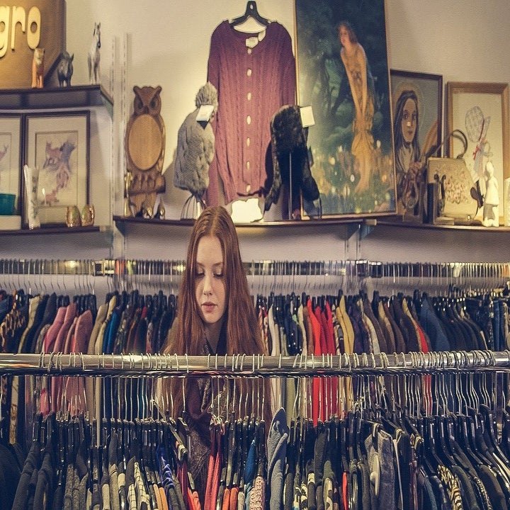 Young woman looking at different racks of clothes at a store.