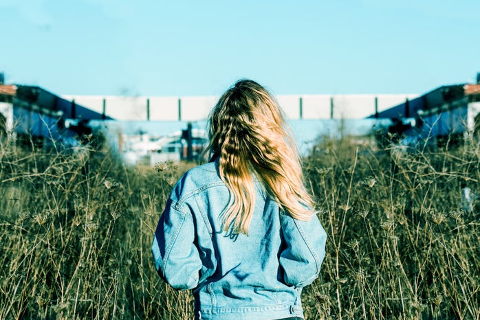 person wearing blue denim jacket standing on grass field