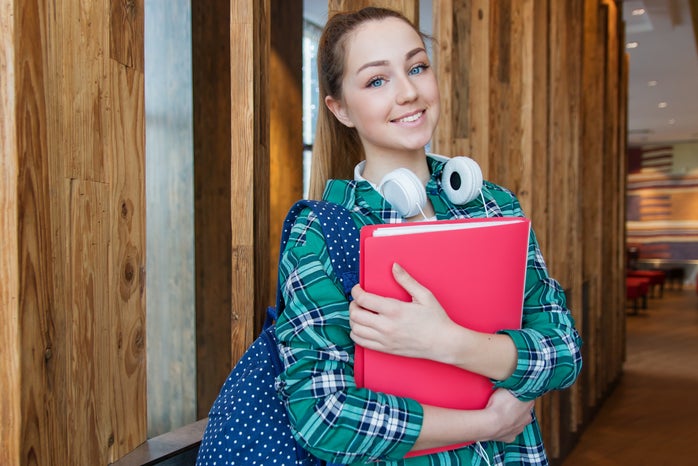 Woman Standing In Hallway While Holding Book