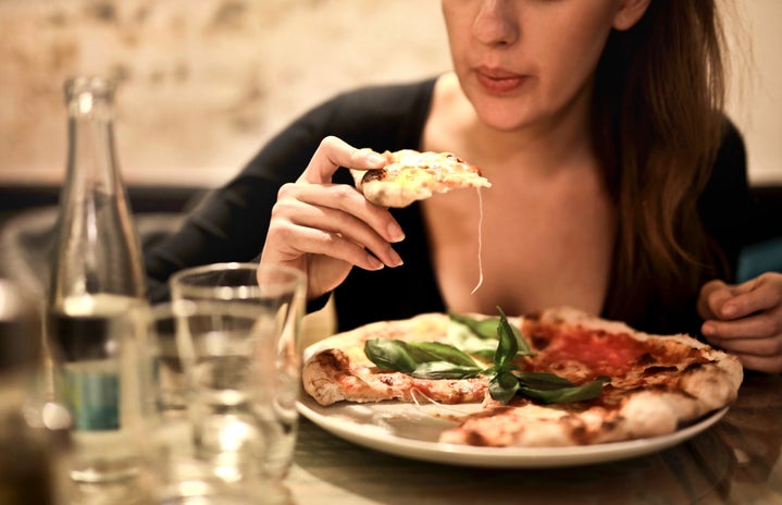 Woman Holds Sliced Pizza Seats By Table With Glass