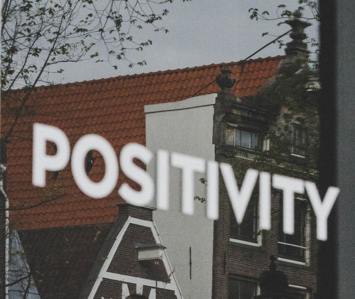 The word \"positivity\" written in white and in all caps in front of the top of a building.