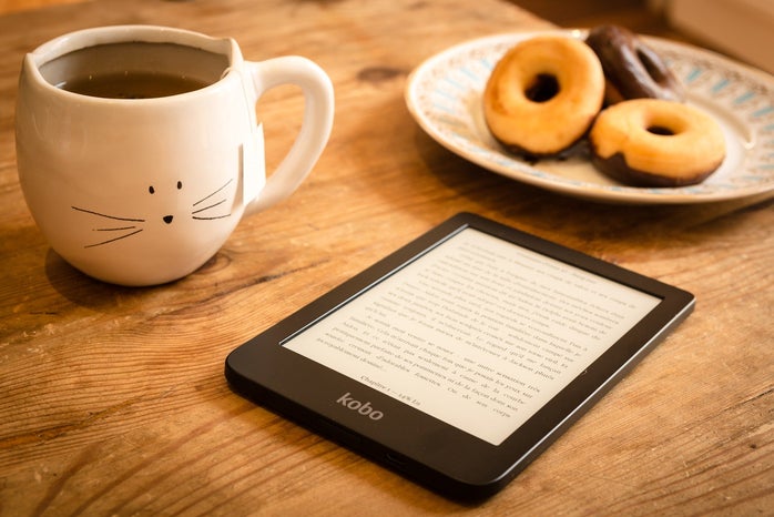 Reading on a tablet with a mug of tea and a plate of donuts