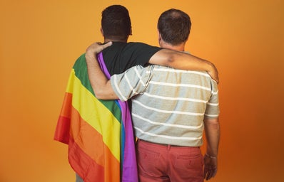 One man with Pride flag, other man hugging him