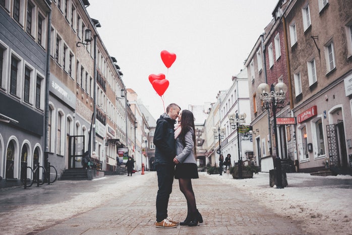 man and woman balloons kissing