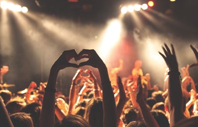 woman at a concert putting hands in a heart shape