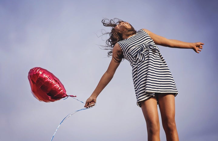 Girl jumping with red heart balloon