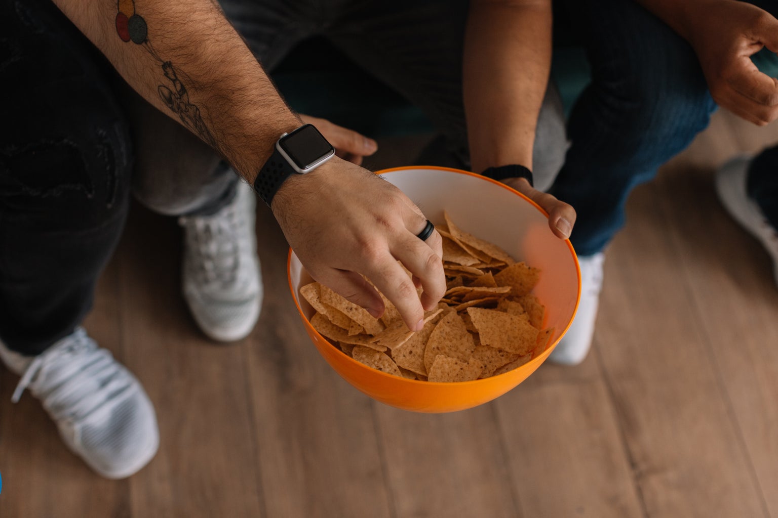 man's hand grabbing a chip out of an orange bowl