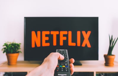 Person pointing remote at a TV that is displaying Netflix