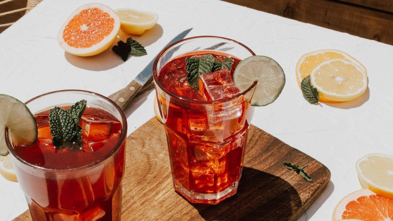 2 drinks in clear glasses surround by sliced fruit