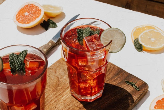 2 drinks in clear glasses surround by sliced fruit