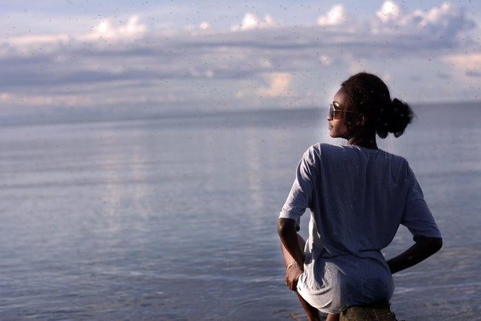profile of black woman in long sleeve shirt with ocean backdrop