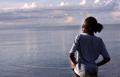 profile of black woman in long sleeve shirt with ocean backdrop