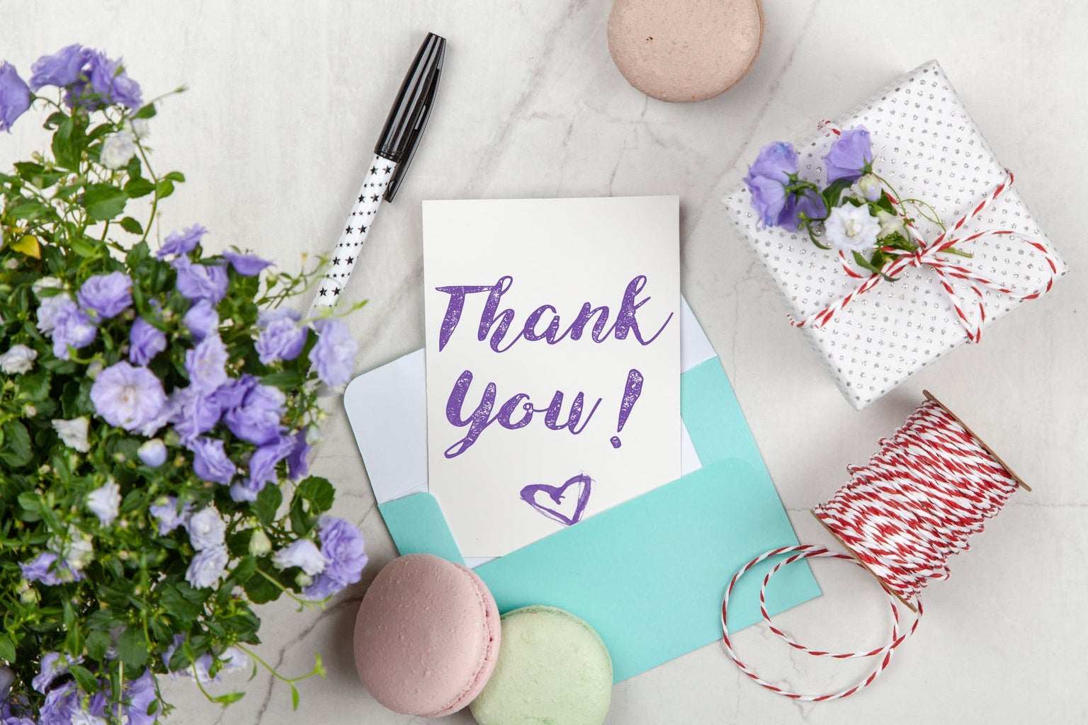 thank you note with pen, gift, cookies, and flowers