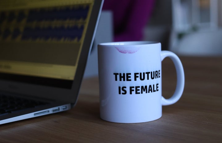 Laptop with white mug that says the future is female with a lipstick mark