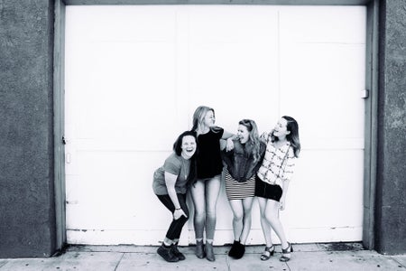 Black and white image of 4 women laughing and holding onto each other