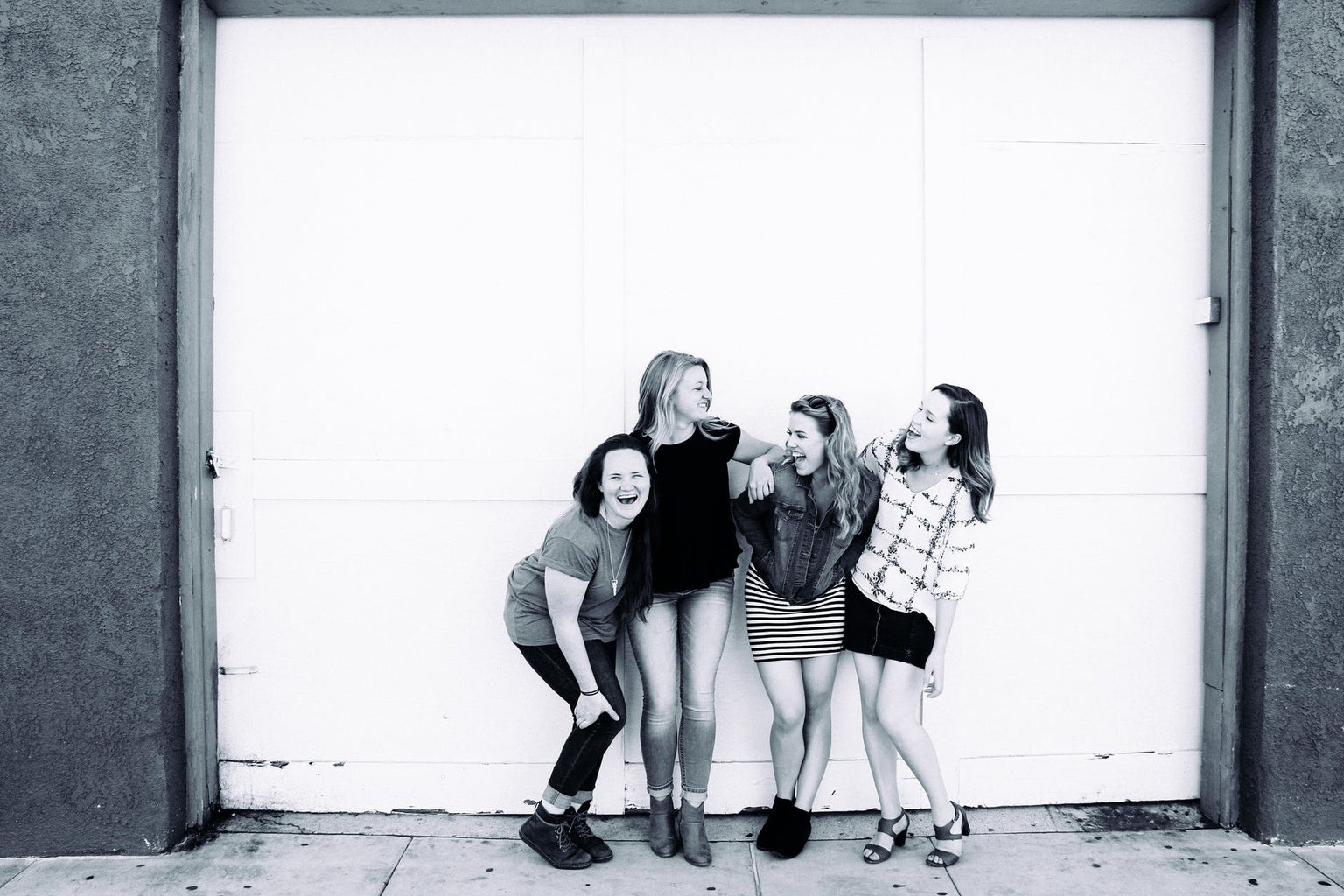 Black and white image of 4 women laughing and holding onto each other