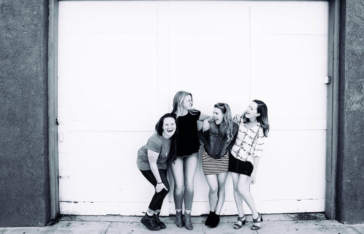 Black and white image of 4 women laughing and holding onto each other