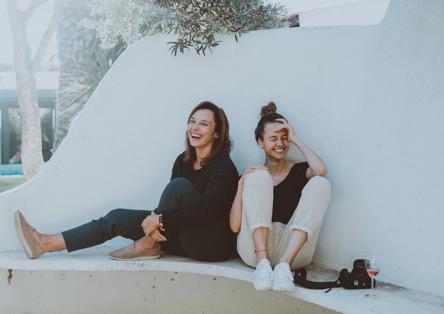 2 women sitting on white bench