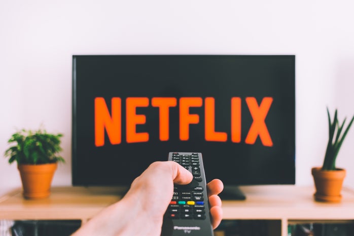 Person pointing a remote at a t.v. that reads Netflix