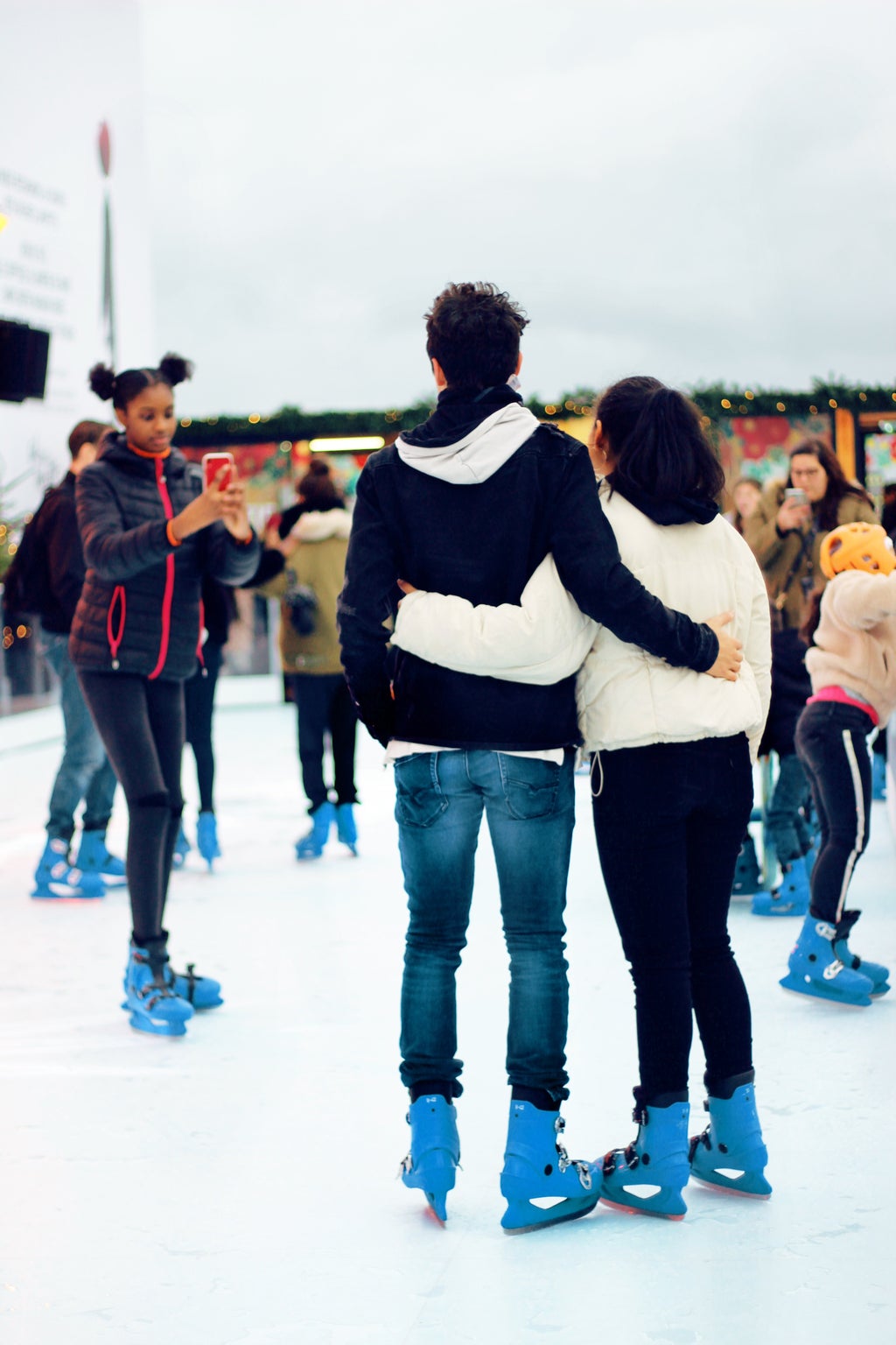 girl taking picture of a couple ice skating