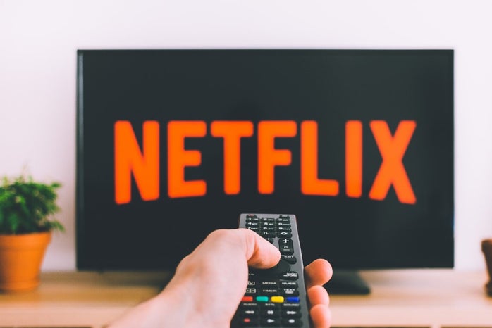 Person holding a remote with a Netflix screen background