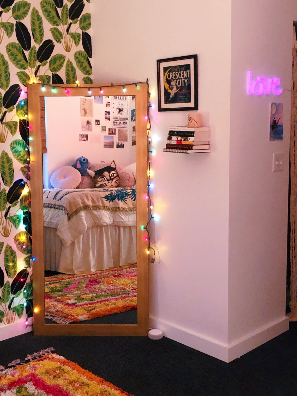 Corner of Ingrid\'s bedroom that shows leafy wallpaper and a large mirror with colorful lights