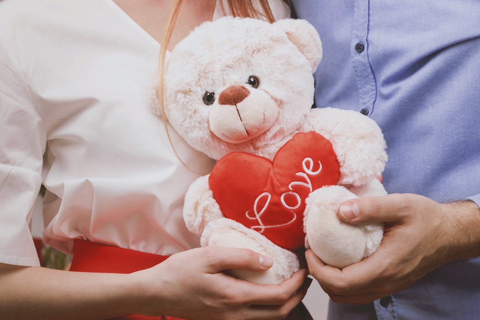 Couple holding a stuffed teddy bear.