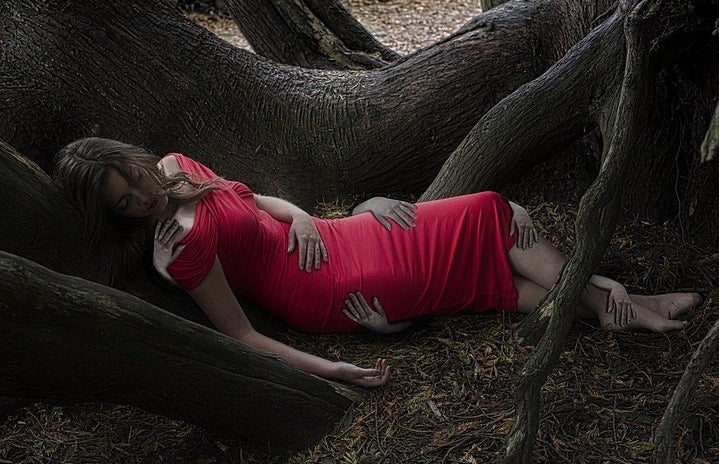 A woman is asleep among tree roots, phantom hands hold parts of her body