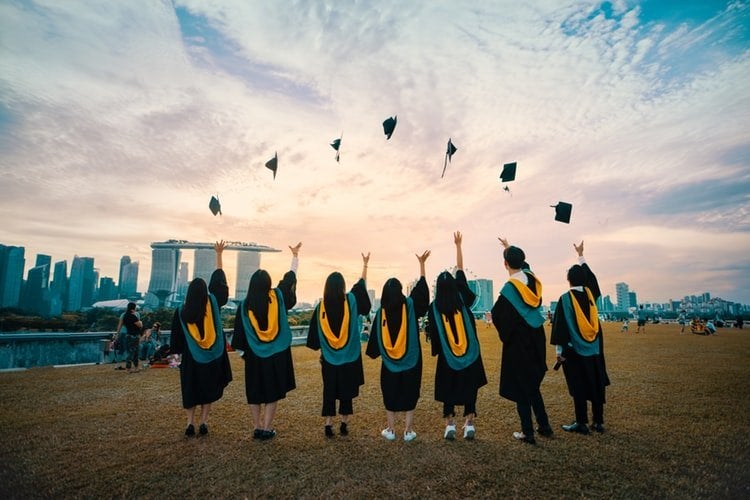 seven graduates throwing their hats