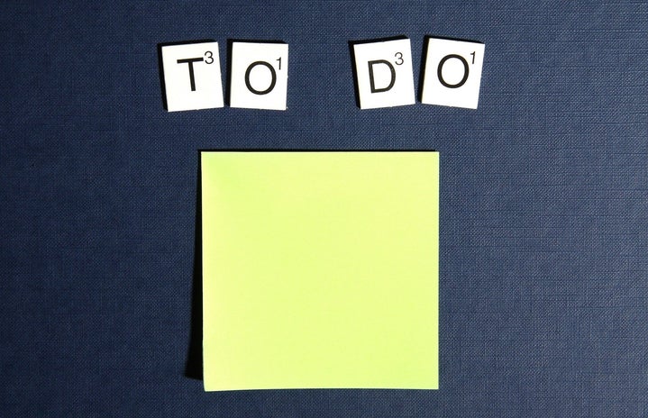 Scrabble tiles spell out \"To Do\" on a blue background above a yellow sticky note