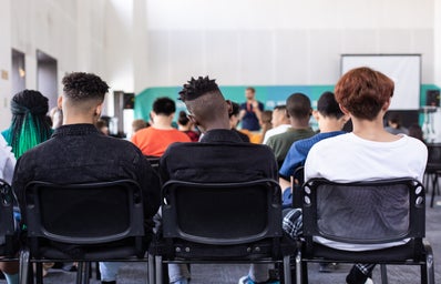 people sitting in chairs in a classroom viewed from behind