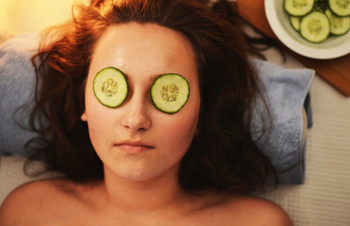 Woman Lying on White Textile With Sliced Cucumbers on Her Eyes