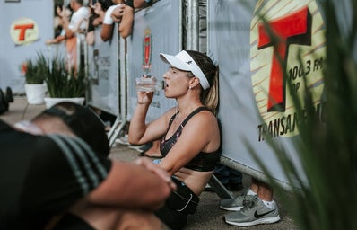 Woman Runner in Black Crop Top Sitting and Drinking Water at Marathon