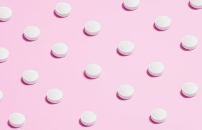 white pills placed on pink backdrop