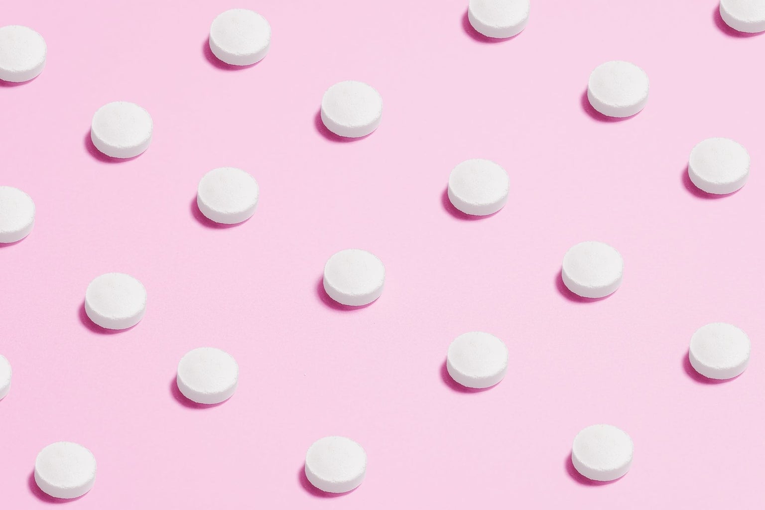 white pills placed on pink backdrop