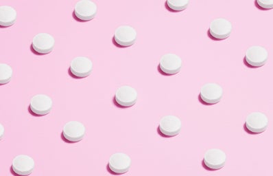 white pills placed on pink backdrop