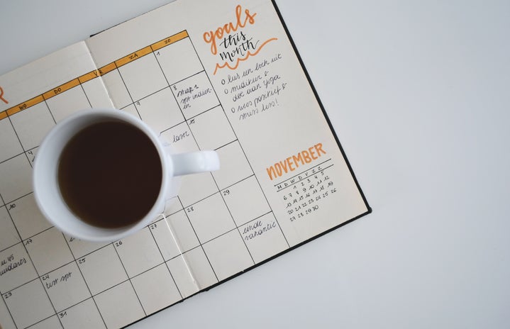 white ceramic mug with coffee on top of a bullet journal