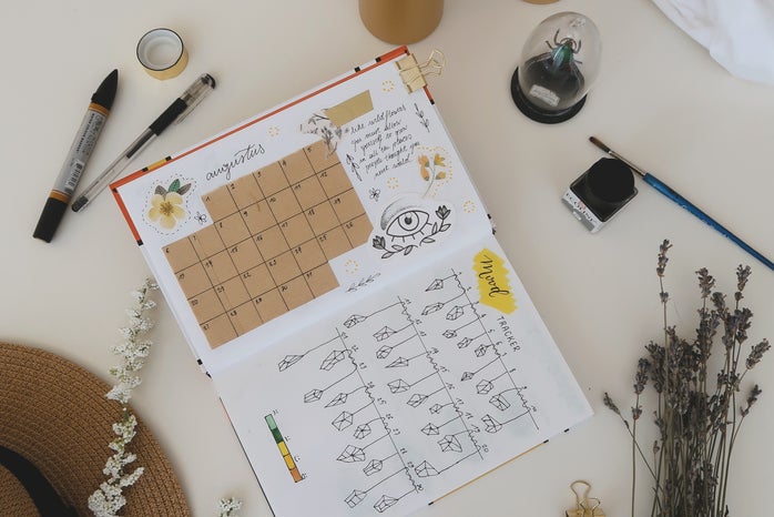 two yellow pillar candles with a bullet journal and art supplies