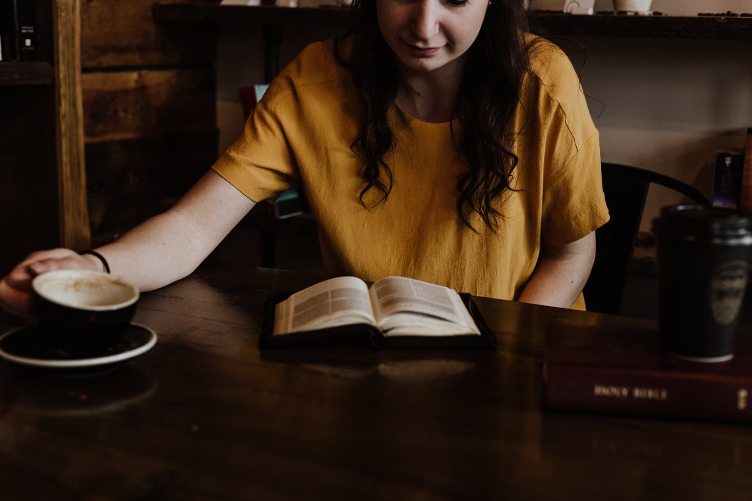 women sitting on a chair in front of book with coffee