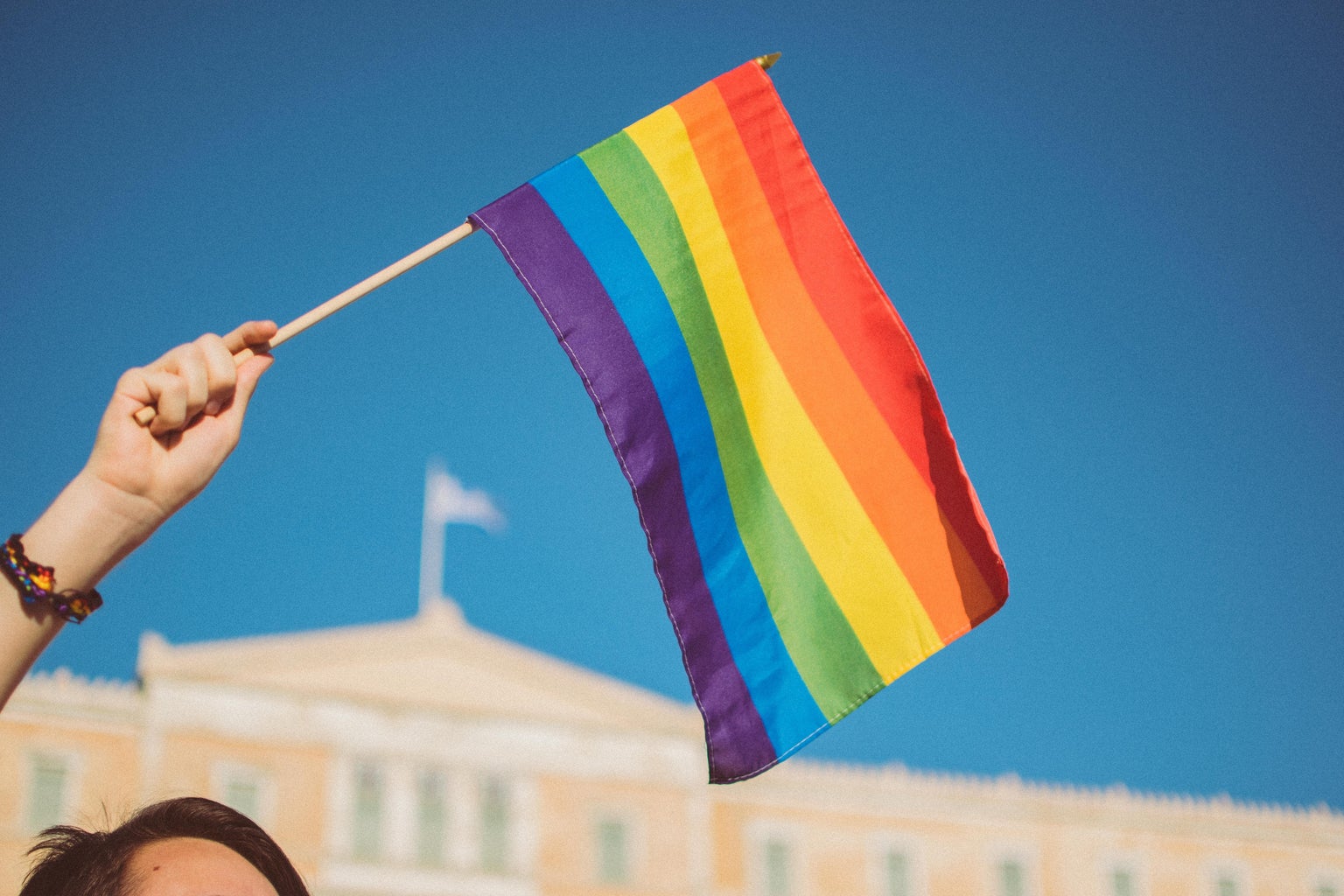 girl holding pride flag with blue sky