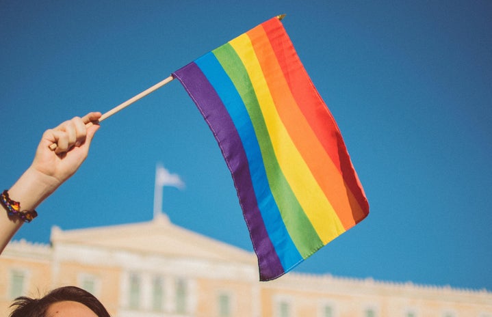 girl holding pride flag with blue sky