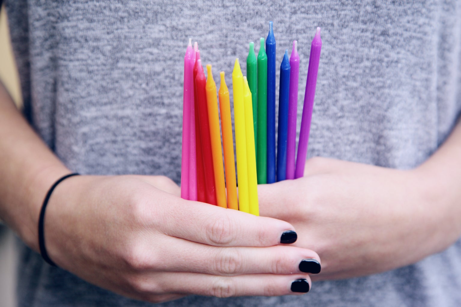 A person holding a collection of colorful birthday candles