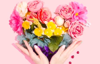 Person holding flowers in shaoe of heart with rainbow colors