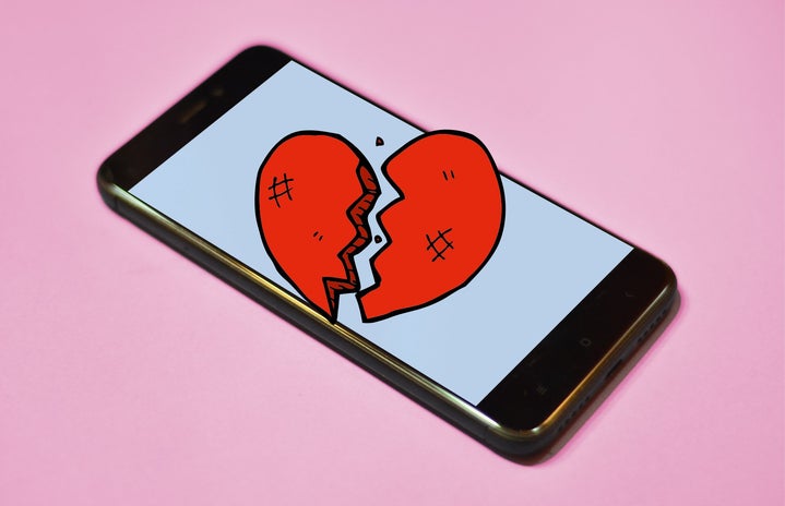 Phone with broken heart and pink background