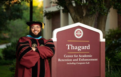 Dr. Starke leaning on \"Thagard\" sign
