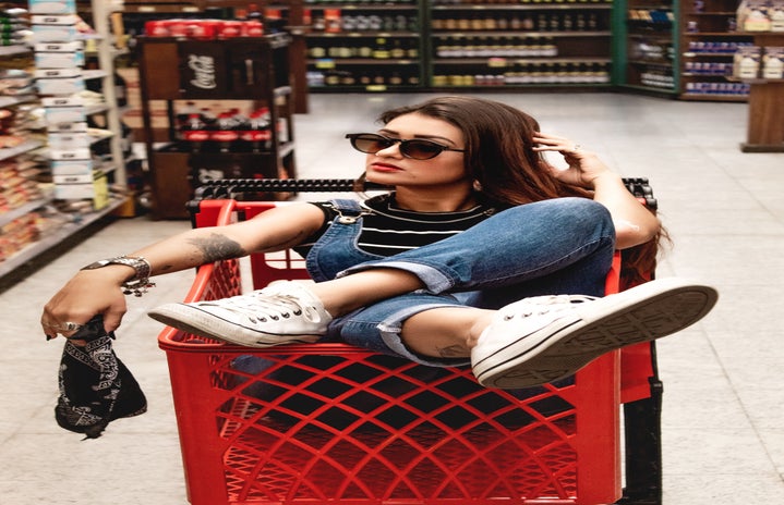 a woman sits in a red shopping cart in the middle of a store