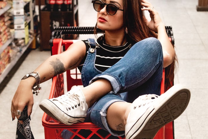 a woman sits in a red shopping cart in the middle of a store